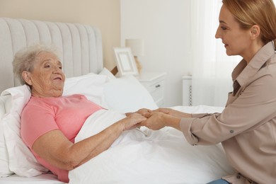 Caregiver supporting senior patient in bedroom at home