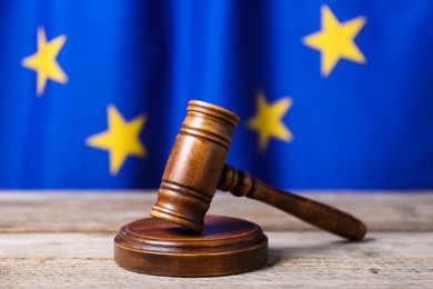 Photo of Judge's gavel on wooden table against European Union flag, closeup