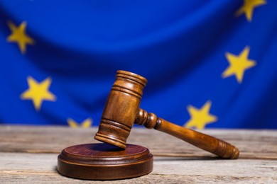 Photo of Judge's gavel on wooden table against European Union flag, closeup