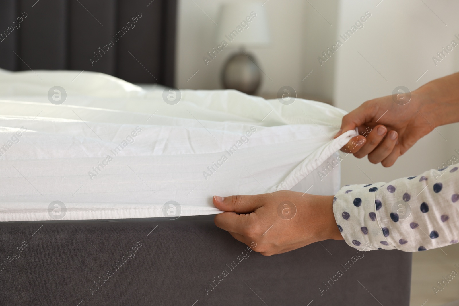 Photo of Woman changing clean bed linens at home, closeup