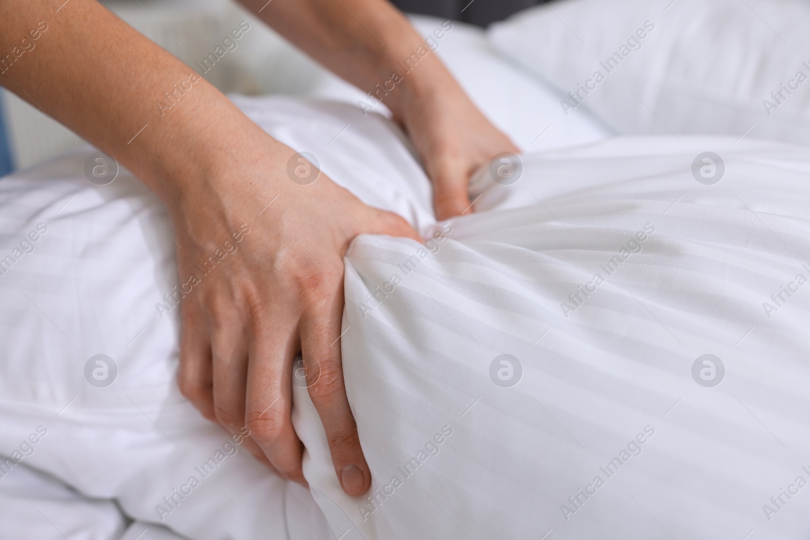 Photo of Woman changing clean bed linens at home, closeup