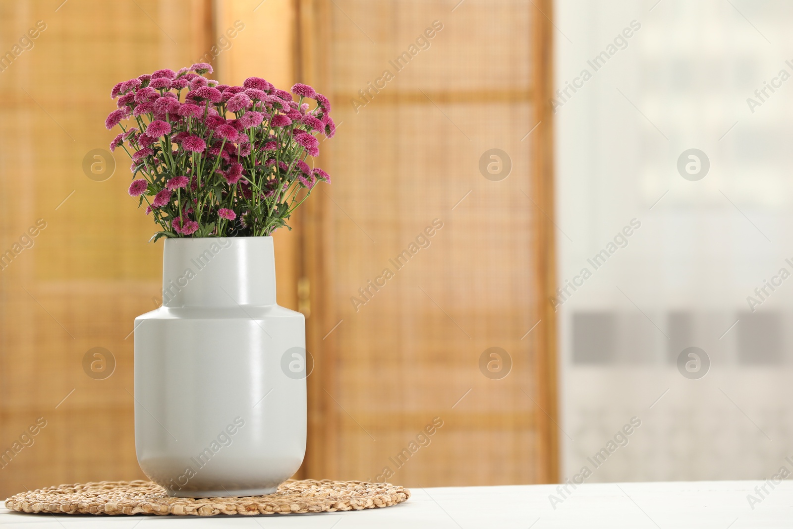 Photo of Beautiful pink flowers in vase on table at home, space for text