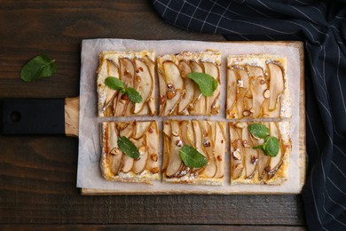 Photo of Tasty puff pastry pie with pears and mint on wooden table, top view