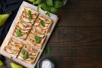 Photo of Tasty puff pastry pie with pears, mint and powdered sugar on wooden table, top view. Space for text