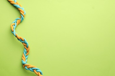 Photo of Colorful ropes tied together on light green background, top view and space for text. Unity concept