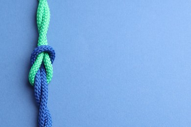 Colorful ropes tied in knot on blue background, top view and space for text. Unity concept