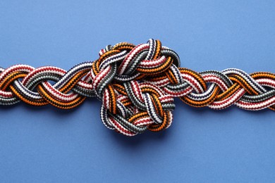 Colorful ropes tied in knot on blue background, top view. Unity concept