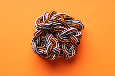 Colorful ropes tied in knot on orange background, top view. Unity concept