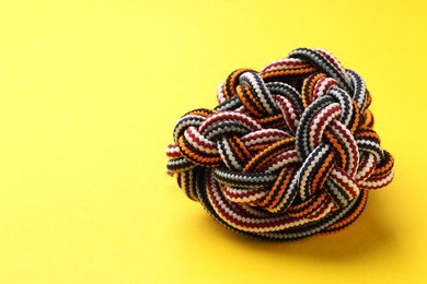 Photo of Colorful ropes tied together on yellow background, closeup and space for text. Unity concept