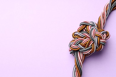 Photo of Colorful ropes tied in knot on violet background, top view and space for text. Unity concept