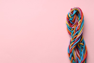 Colorful ropes tied together on pink background, top view and space for text. Unity concept