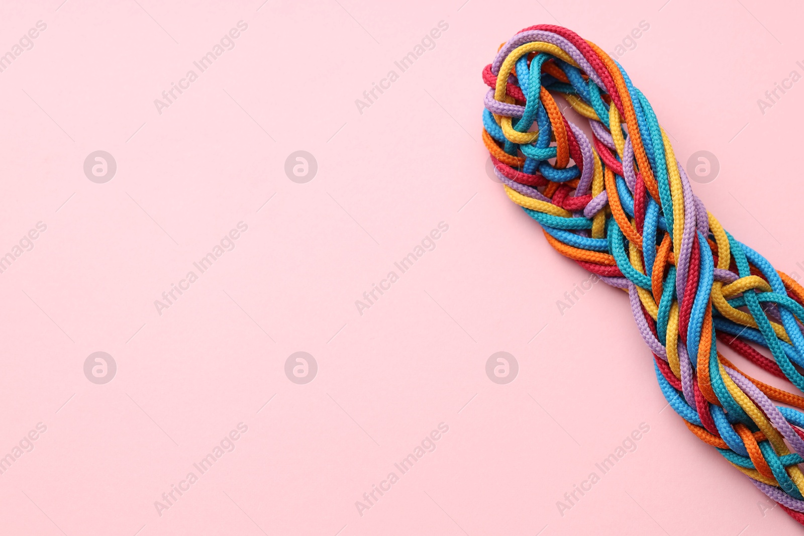 Photo of Colorful ropes tied together on pink background, top view and space for text. Unity concept