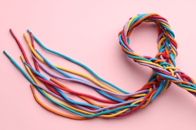 Photo of Colorful ropes tied together on pink background, top view. Unity concept