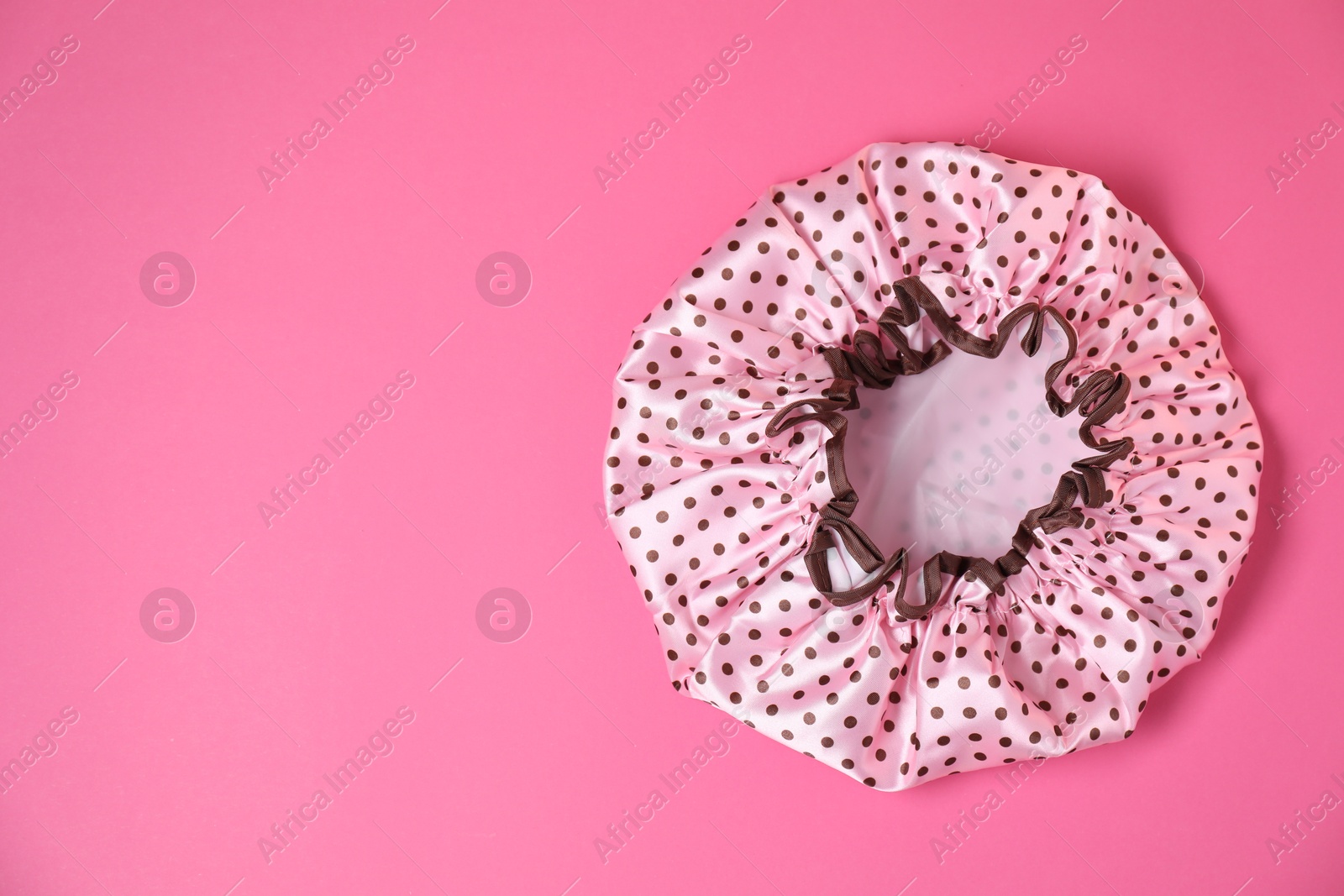 Photo of One shower cap on pink background, top view. Space for text