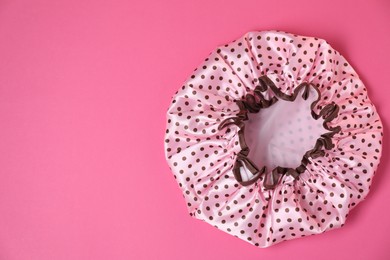 Photo of One shower cap on pink background, top view. Space for text