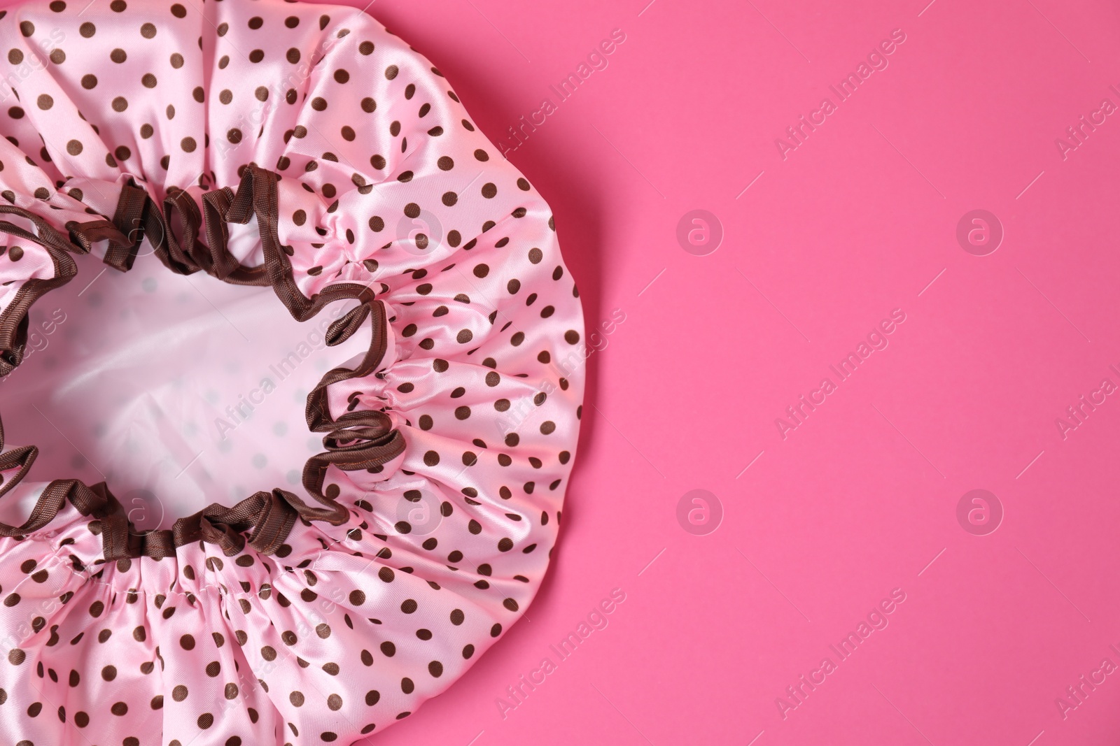 Photo of One shower cap on pink background, top view. Space for text