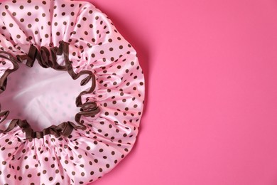 Photo of One shower cap on pink background, top view. Space for text