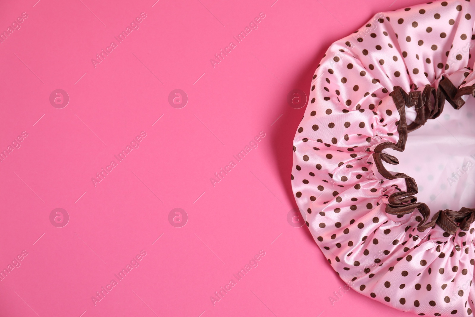 Photo of One shower cap on pink background, top view. Space for text