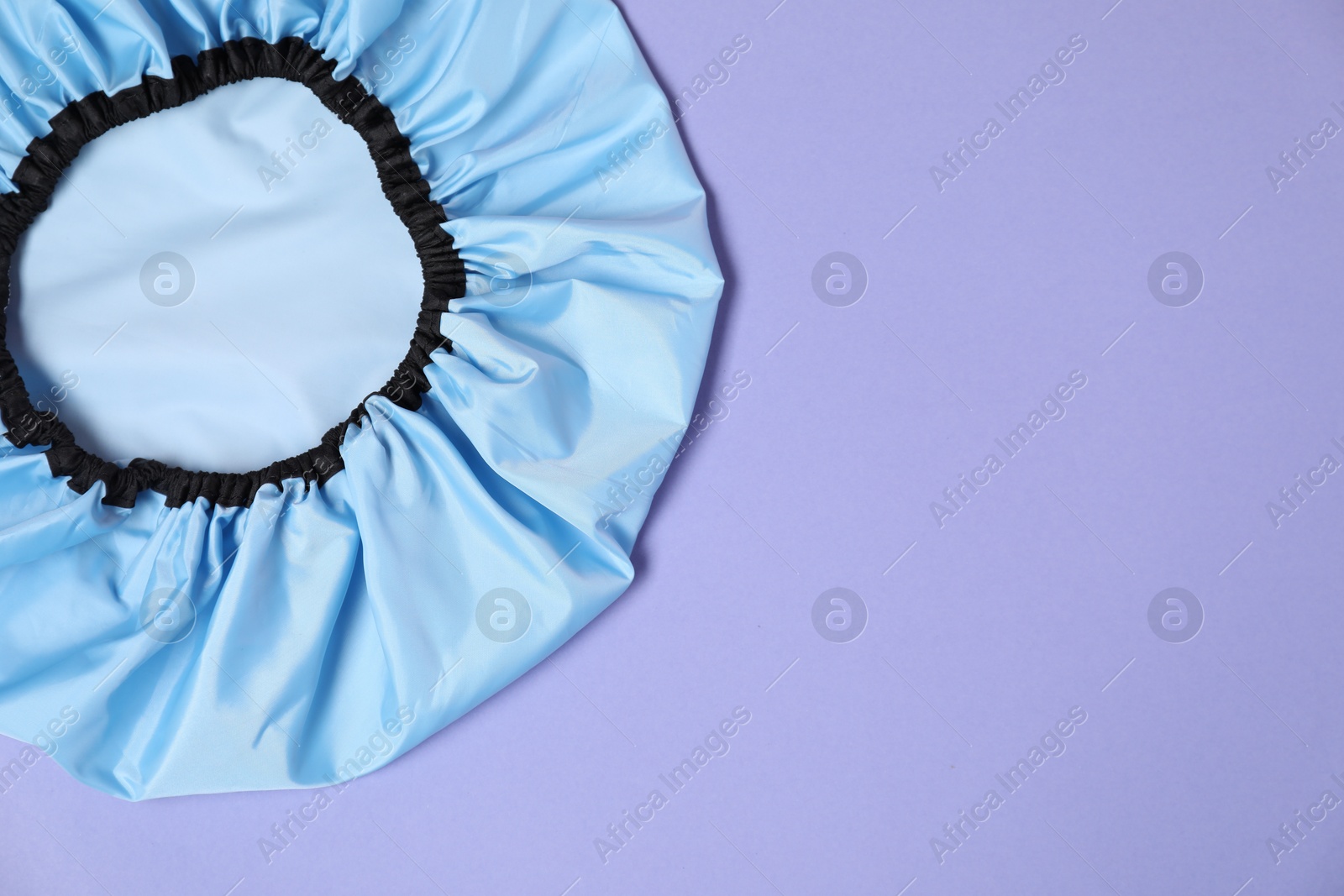 Photo of One shower cap on lilac background, top view. Space for text