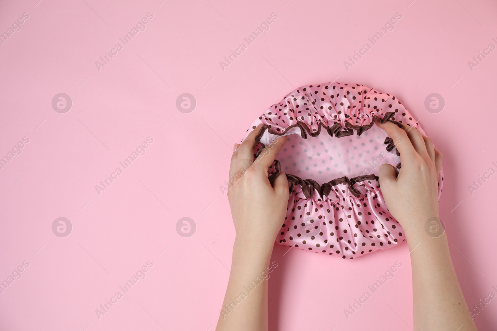 Photo of Woman with shower cap on pink background, top view. Space for text