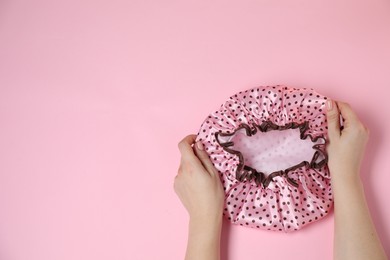 Photo of Woman with shower cap on pink background, top view. Space for text