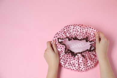 Photo of Woman with shower cap on pink background, top view. Space for text