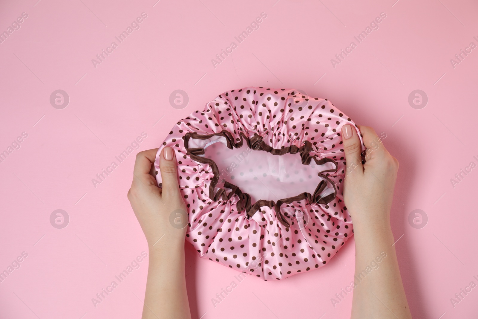 Photo of Woman with shower cap on pink background, top view