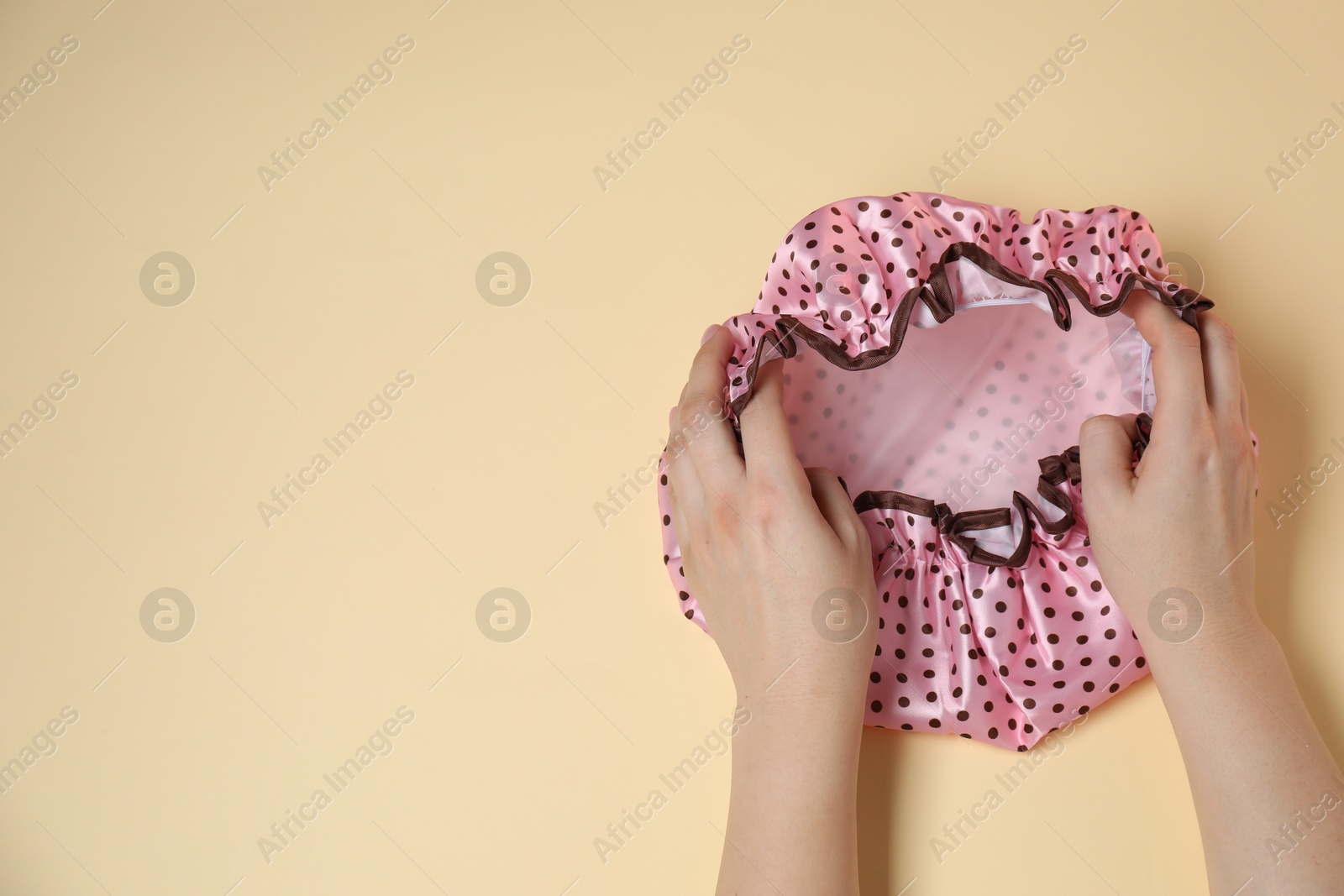 Photo of Woman with shower cap on beige background, top view. Space for text