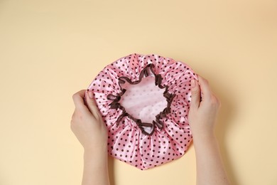 Photo of Woman with shower cap on beige background, top view