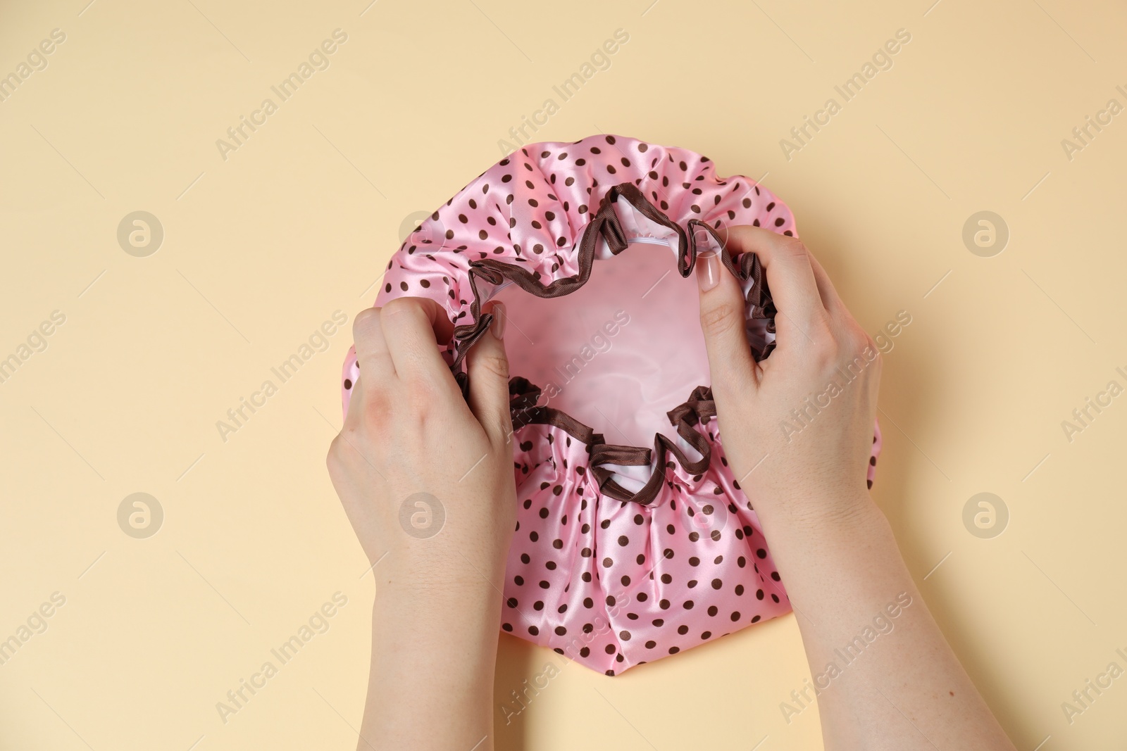 Photo of Woman with shower cap on beige background, top view