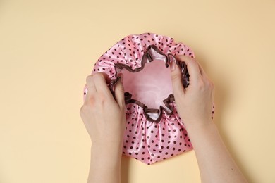 Photo of Woman with shower cap on beige background, top view