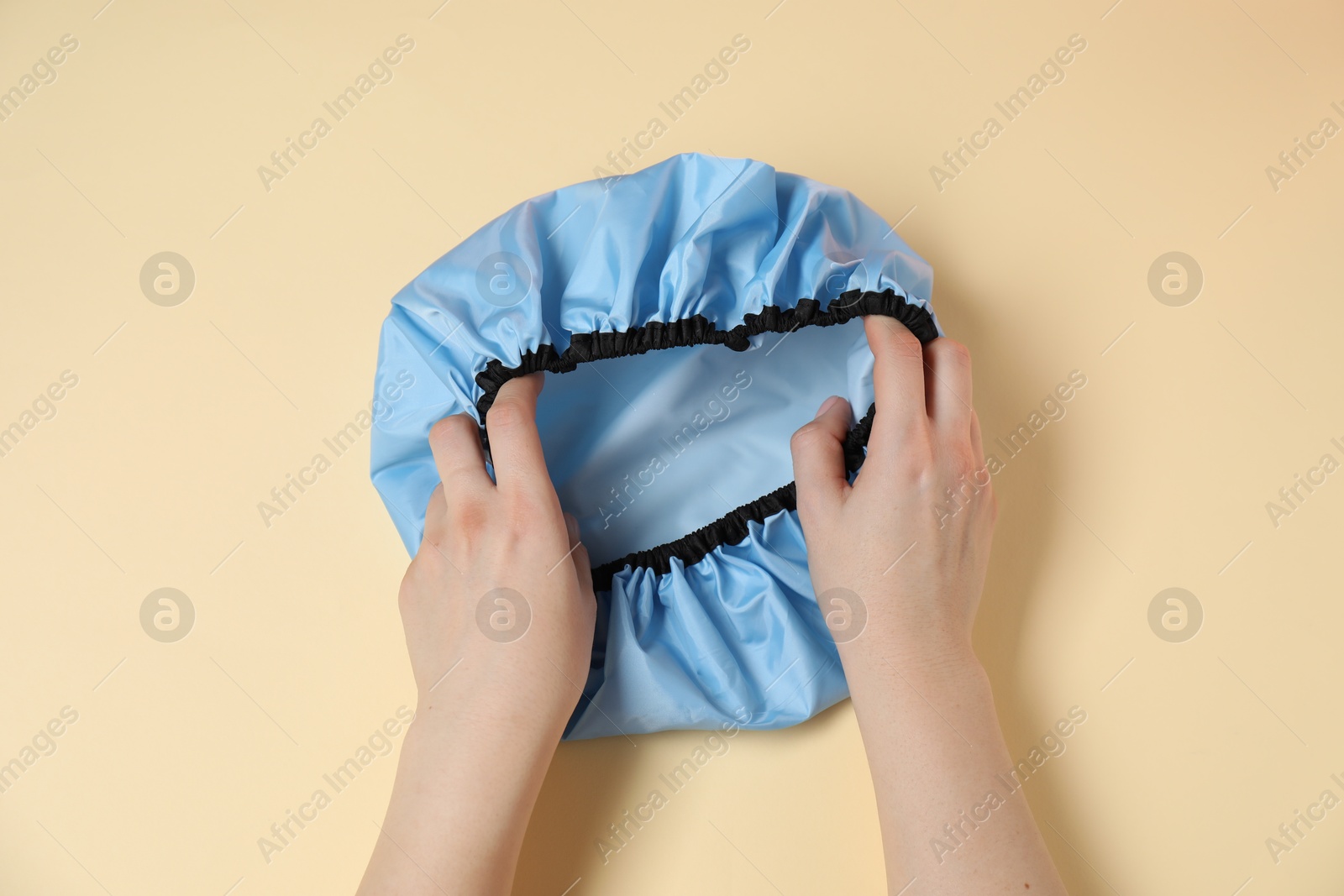 Photo of Woman with shower cap on beige background, top view