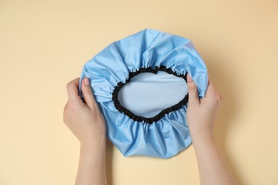 Photo of Woman with shower cap on beige background, top view