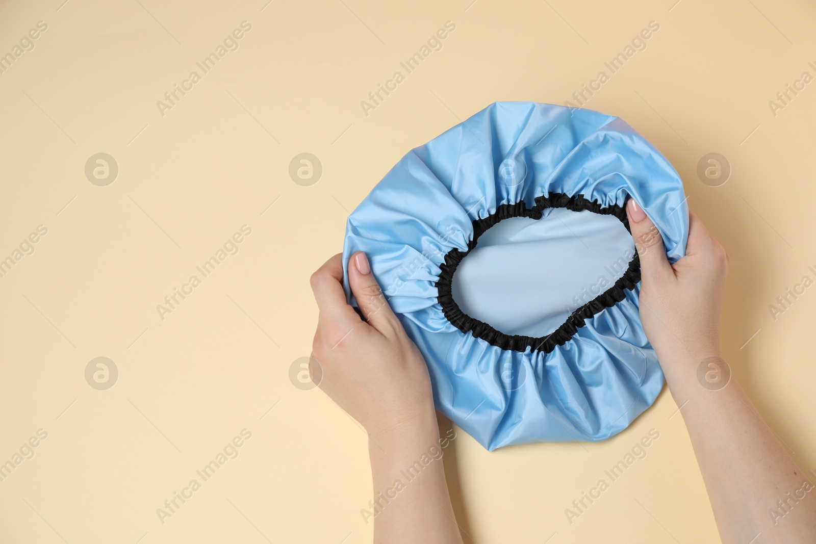 Photo of Woman with shower cap on beige background, top view. Space for text