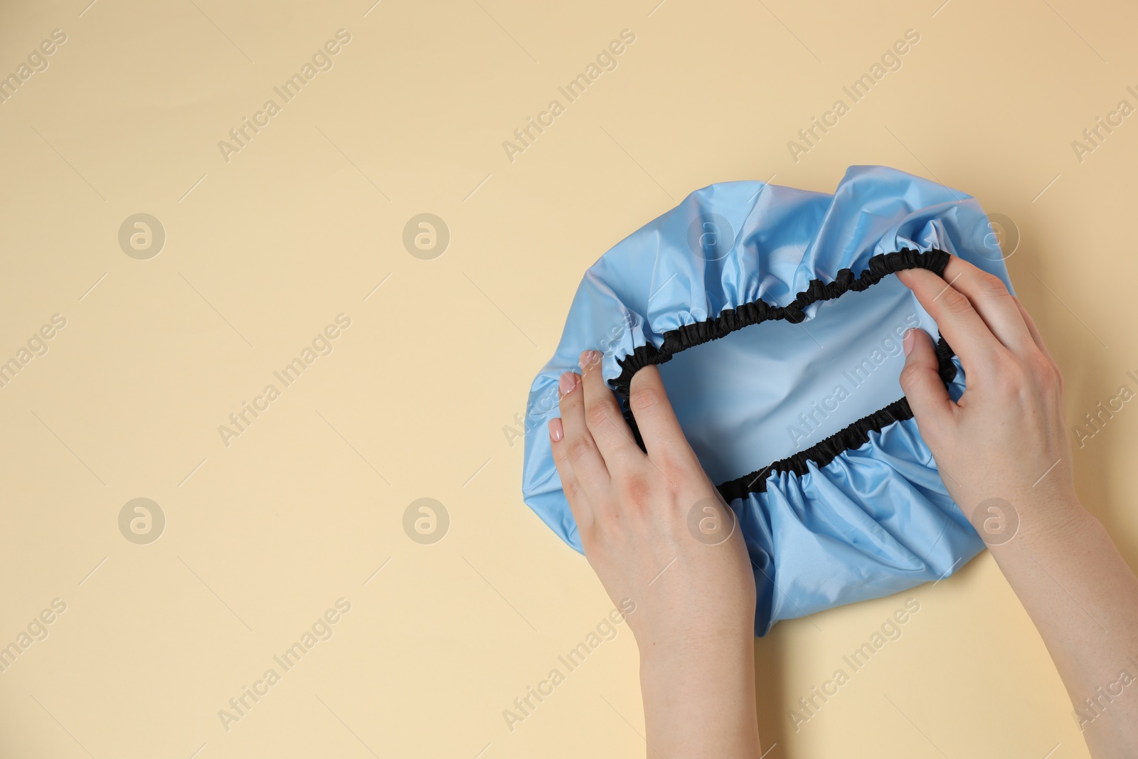 Photo of Woman with shower cap on beige background, top view. Space for text