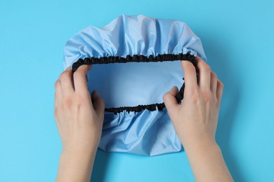 Photo of Woman with shower cap on light blue background, top view