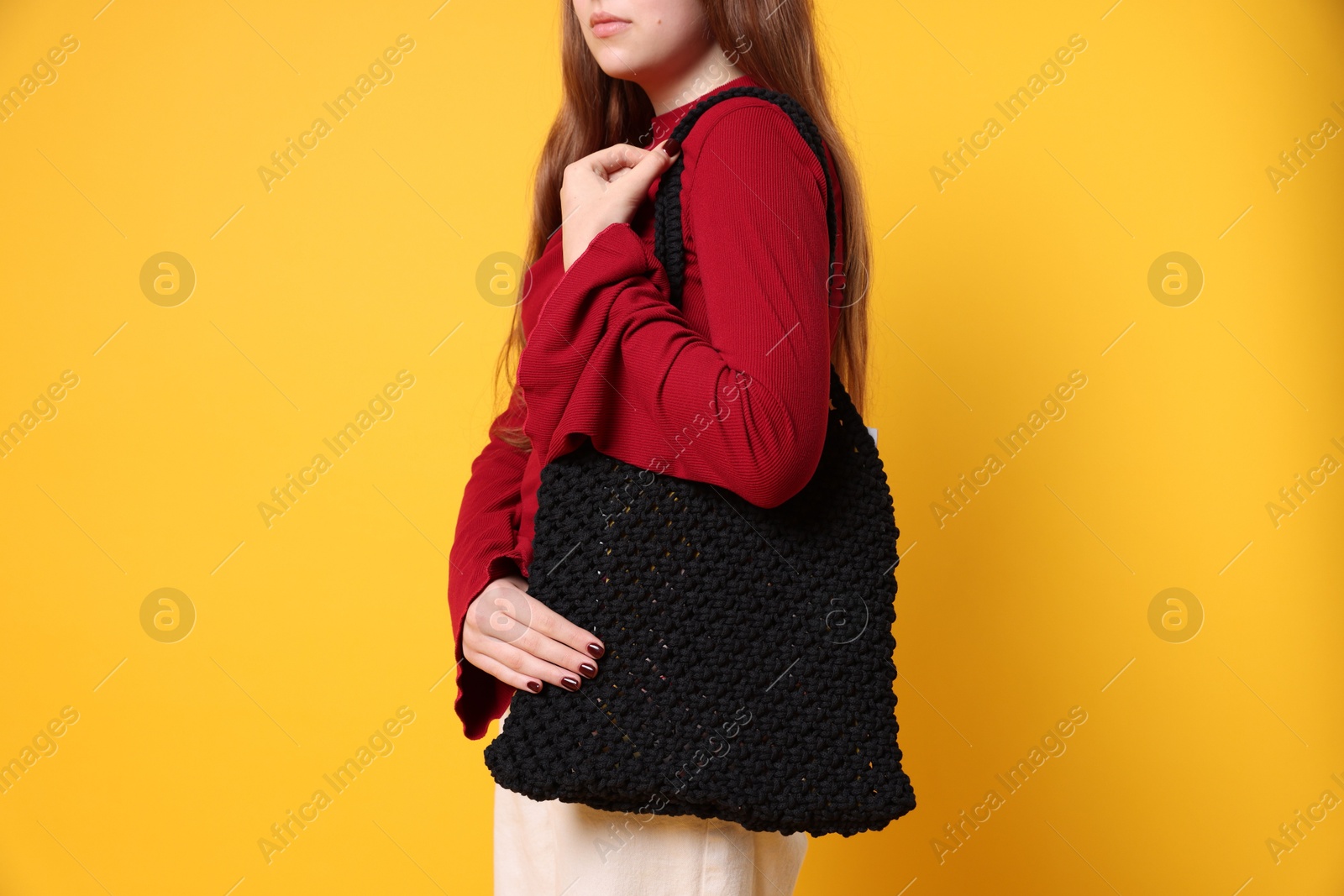 Photo of Teenage girl with handmade macrame bag on yellow background, closeup