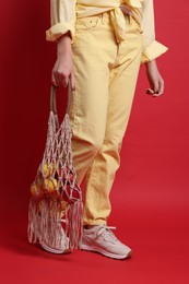 Photo of Teenage girl with handmade macrame bag on red background, closeup