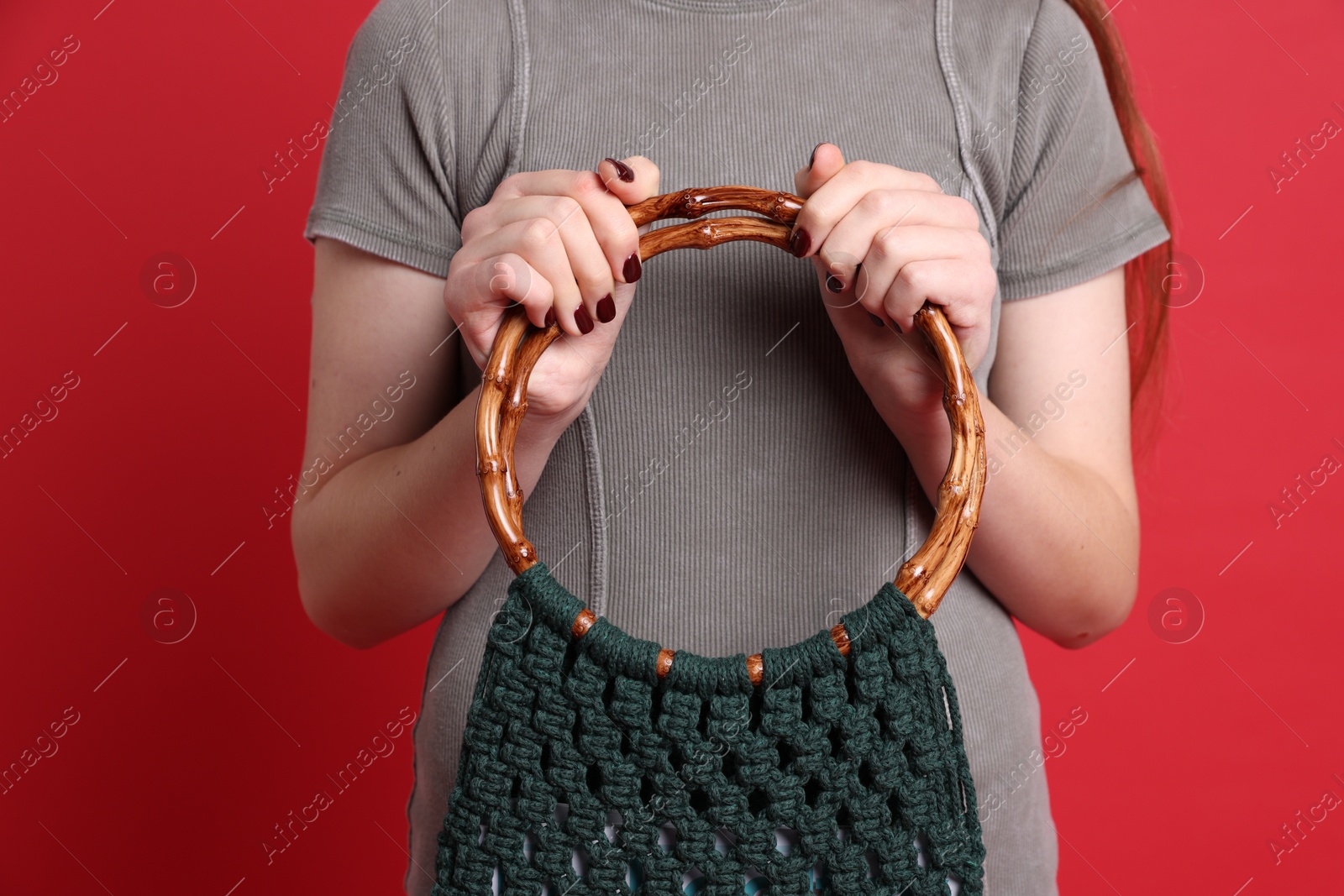 Photo of Teenage girl with handmade macrame bag on red background, closeup