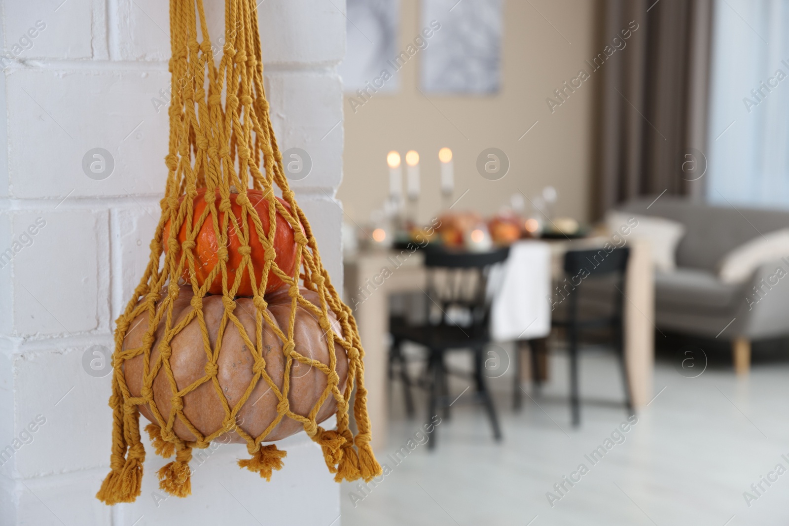 Photo of Macrame bag with products hanging on white brick wall indoors