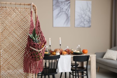 Photo of Macrame bag with fruits on folding screen indoors