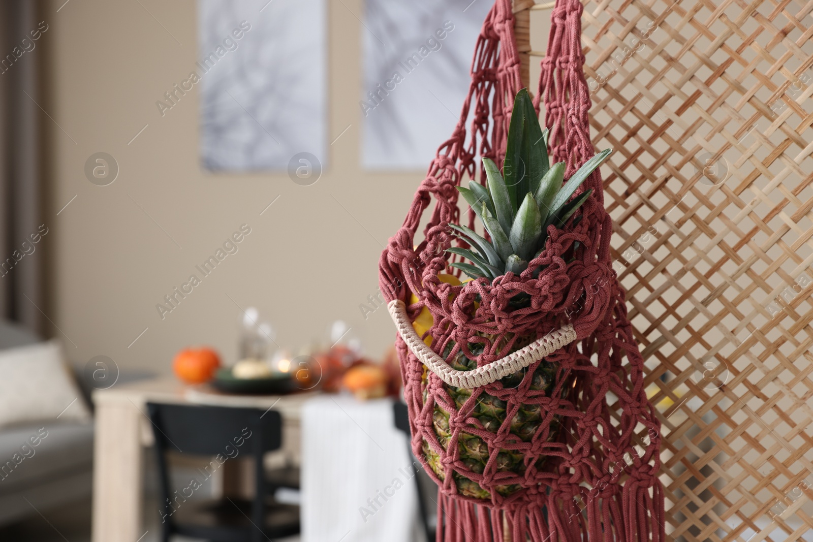 Photo of Macrame bag with fruits on folding screen indoors