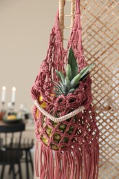 Photo of Macrame bag with fruits on folding screen indoors