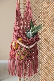 Photo of Macrame bag with fruits on folding screen indoors