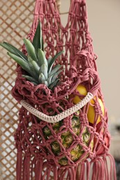 Photo of Macrame bag with fruits on folding screen indoors, closeup