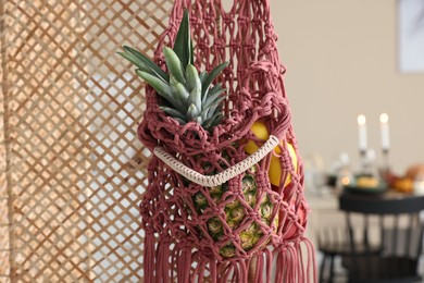 Photo of Macrame bag with fruits on folding screen indoors, closeup