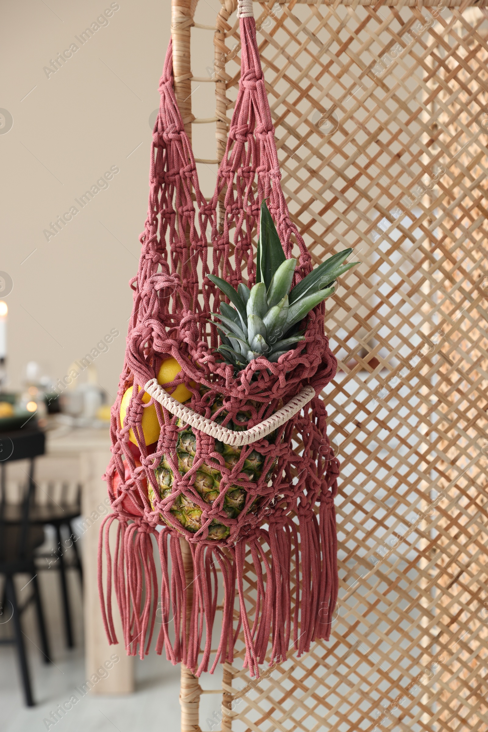 Photo of Macrame bag with fruits on folding screen indoors