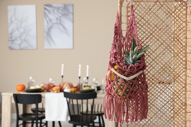 Photo of Macrame bag with fruits on folding screen indoors