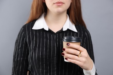 Photo of Teenage girl with cup of coffee wearing stylish ring on grey background, closeup