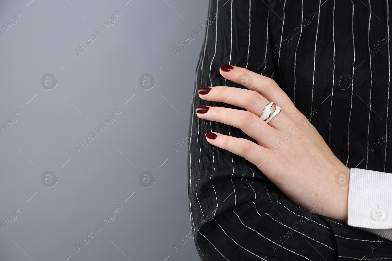 Photo of Teenage girl wearing stylish ring on grey background, closeup. Space for text